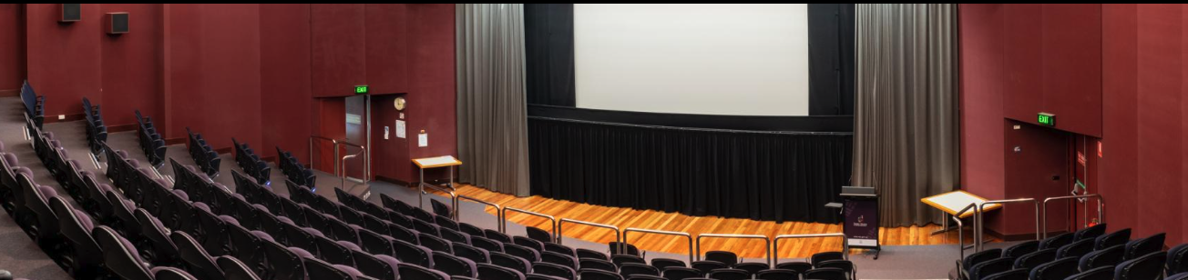 A lecture theatre with stage and large white screen